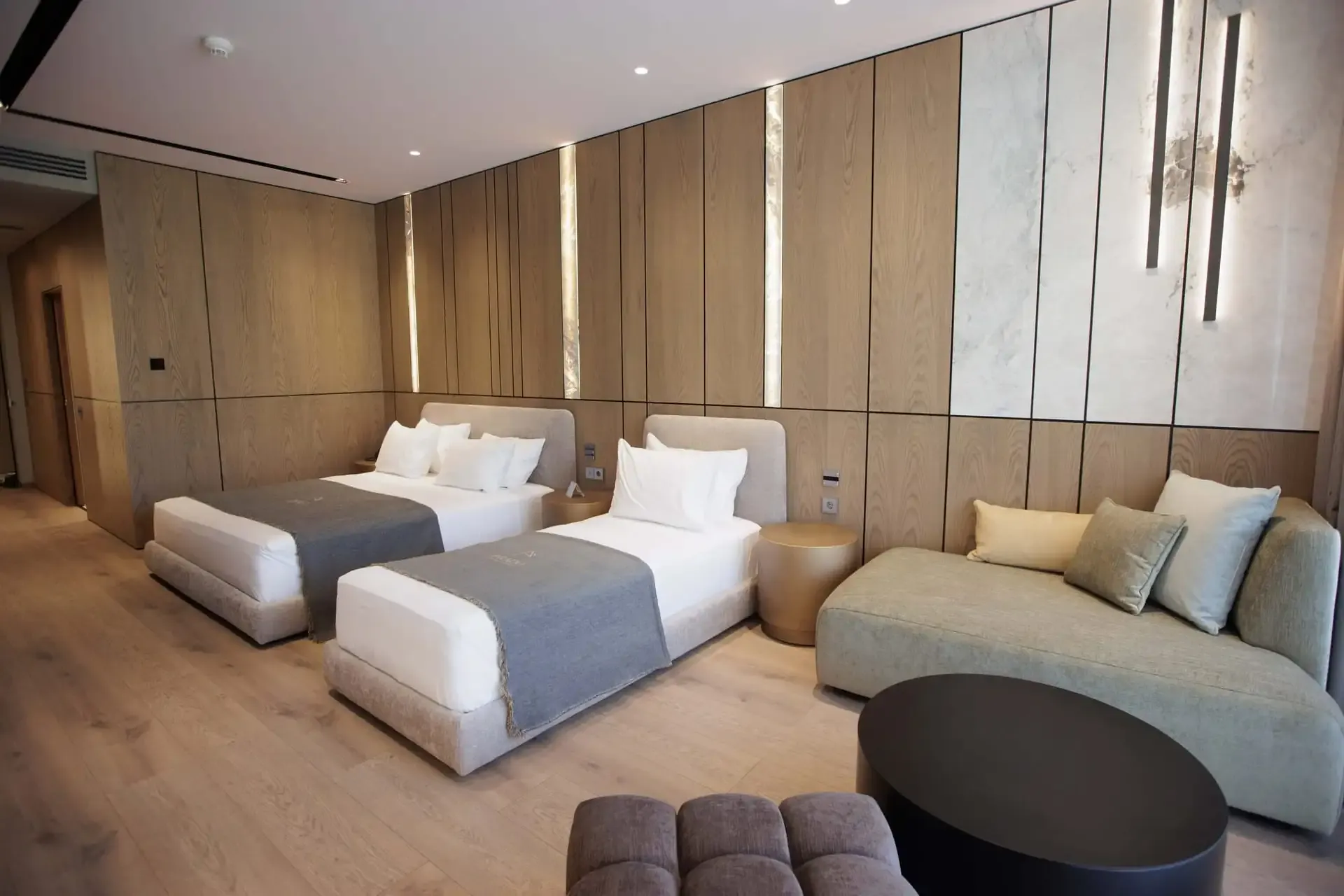 Two single beds and a long upholstered sofa against the oak-panelled wall of a Family Standard Room