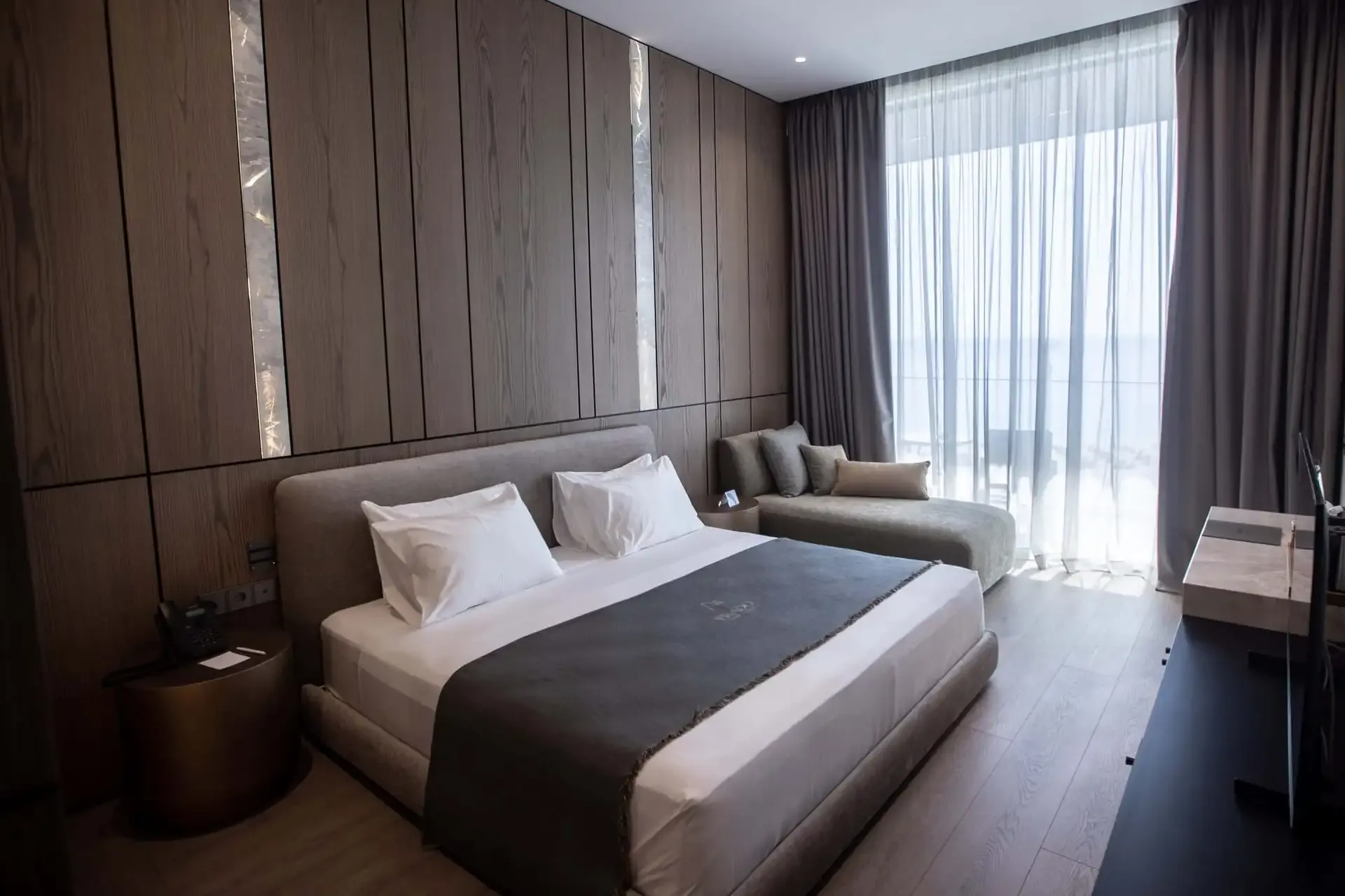 A sea-facing Junior Suite with the bed, a sofa and floor-to-ceiling glazing