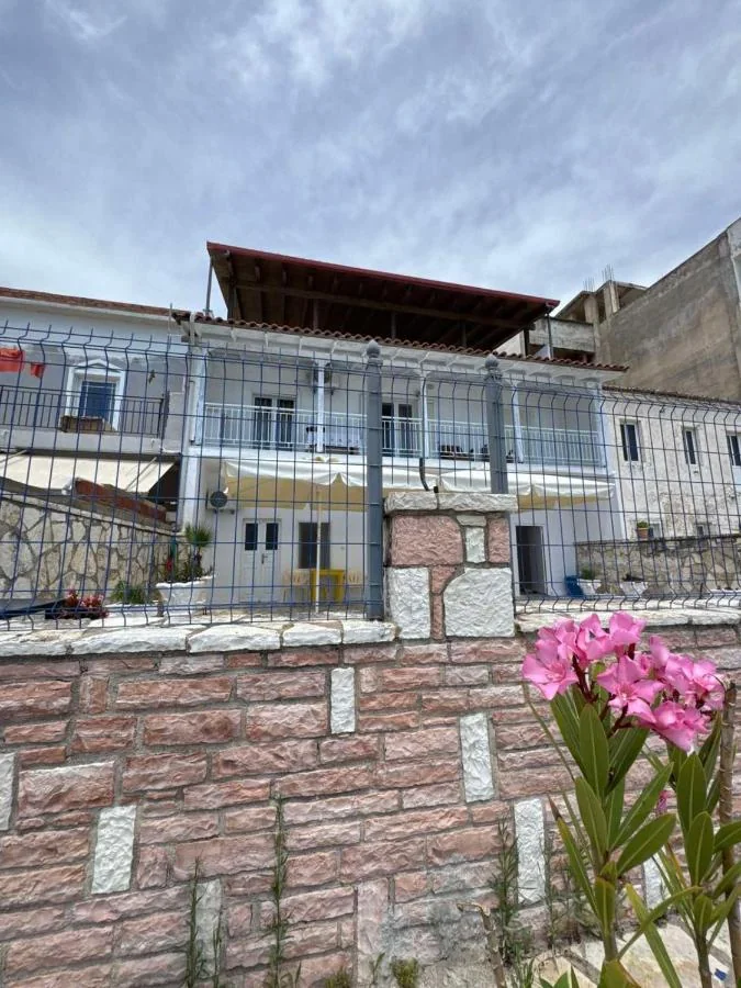 The upper balconies and awnings seen through the slate-blue mesh fence above the stone wall