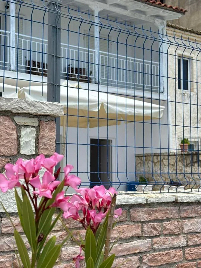 Pink oleander in flower against the stone wall, with the balconies and a cream awning behind