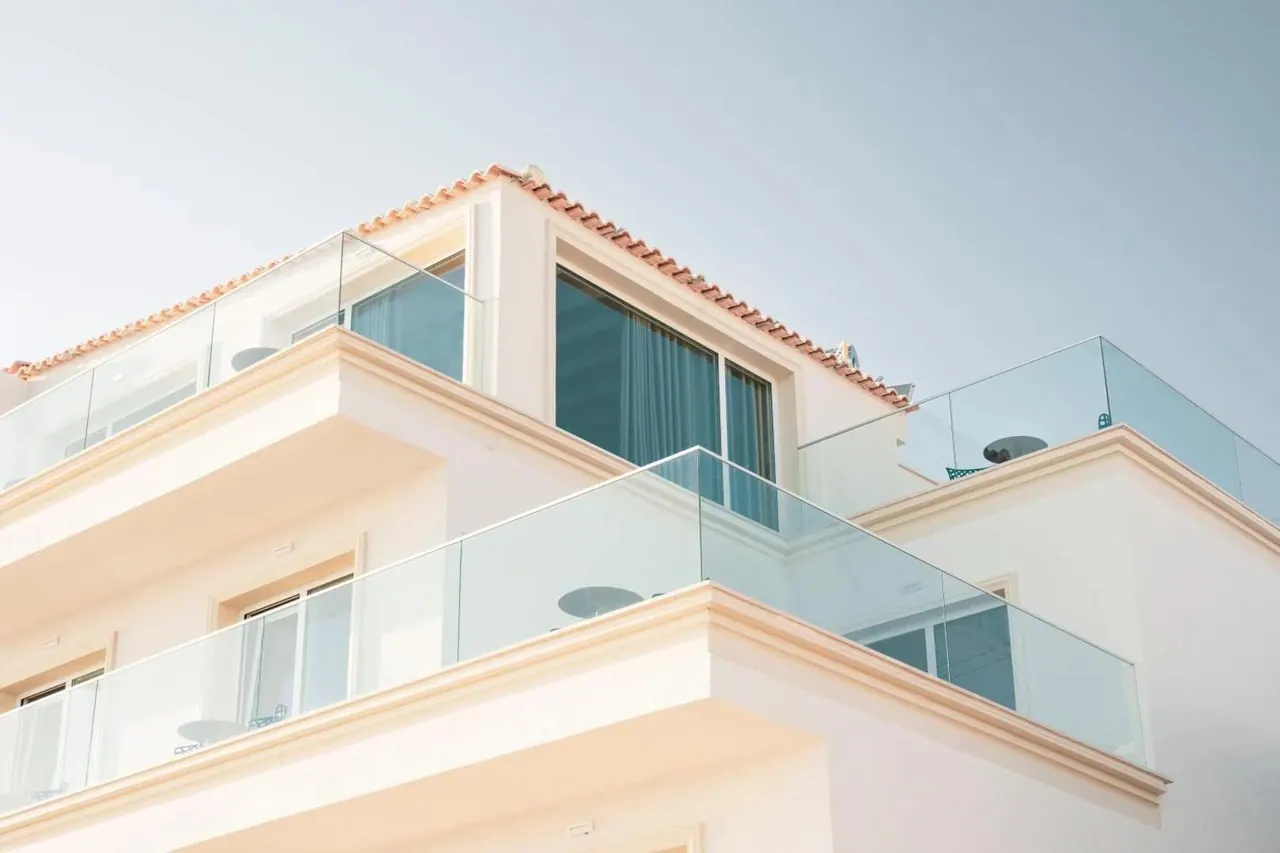 The top floor seen from below: cream cornices, terracotta pantiles and glass balustrades against the sky