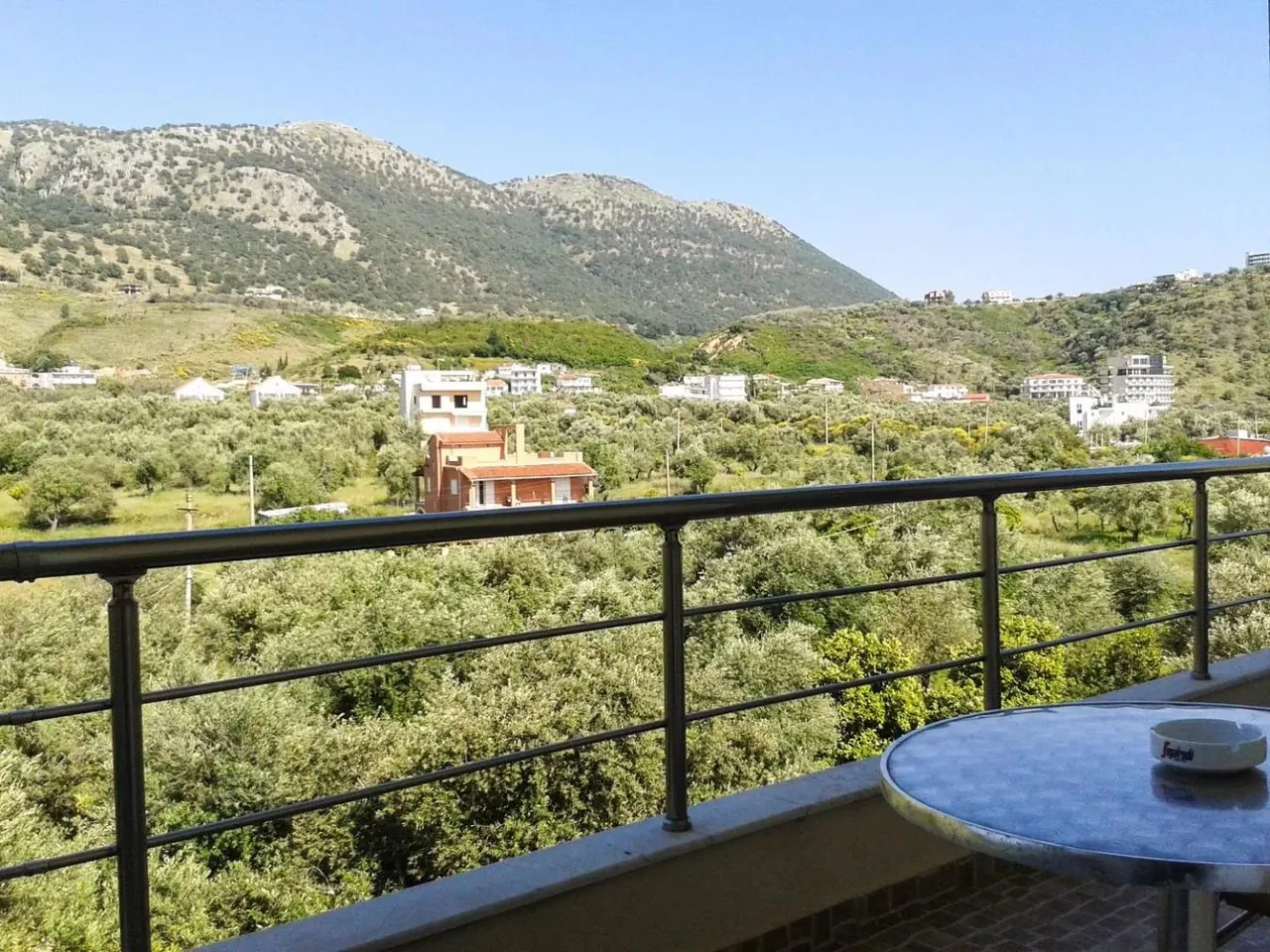 A balcony table looking over olive trees to the green limestone ridge behind Potam