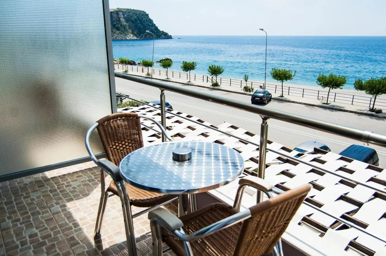 A round balcony table and wicker chairs looking over the coast road to the water