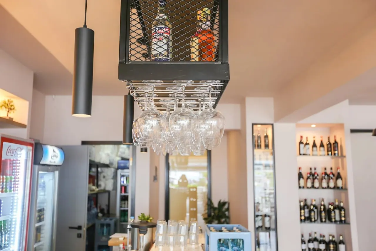 The back bar with hanging glassware, spirit bottles and a black pendant lamp