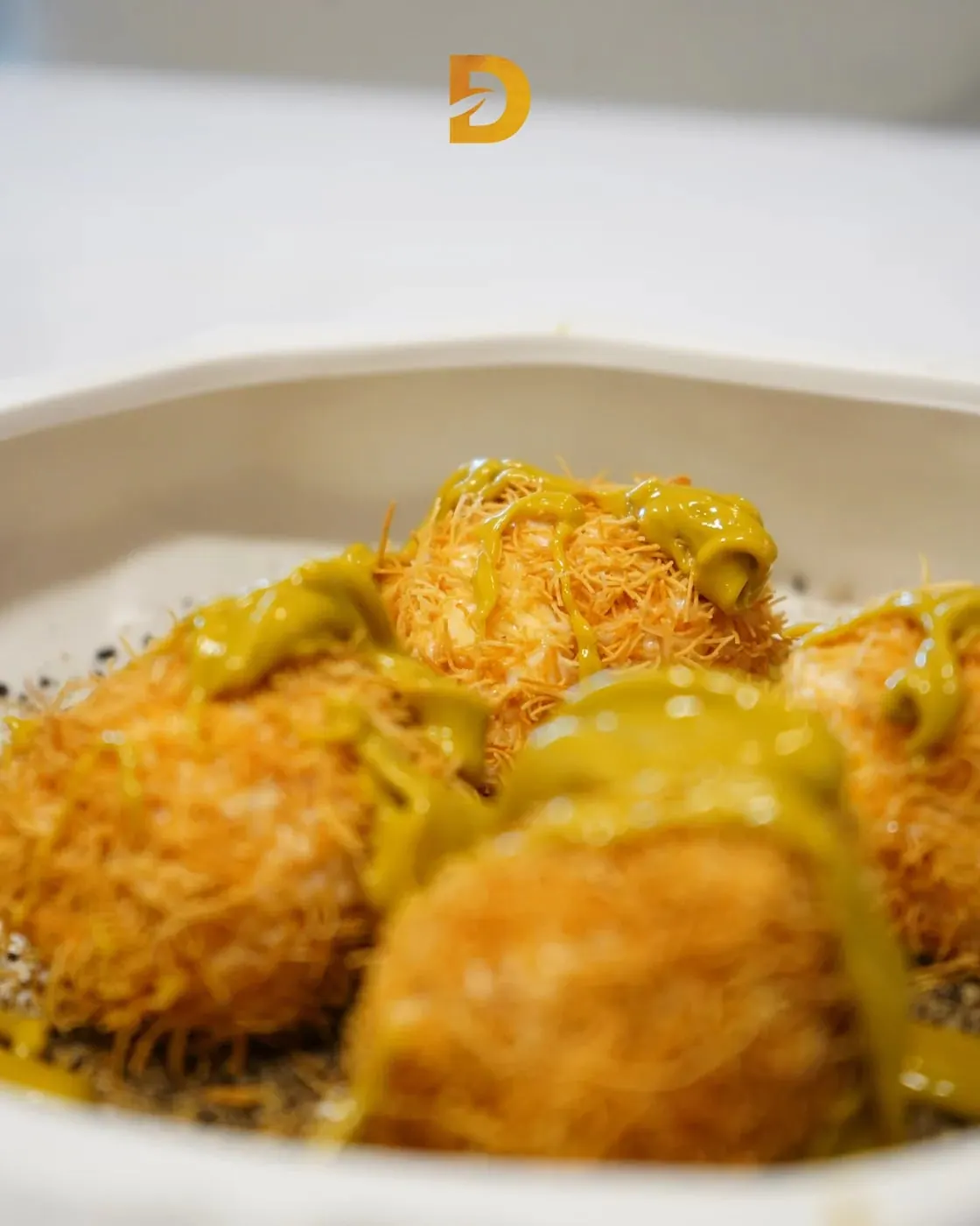 Parcels wrapped in crisp shredded kataifi pastry under a yellow sauce