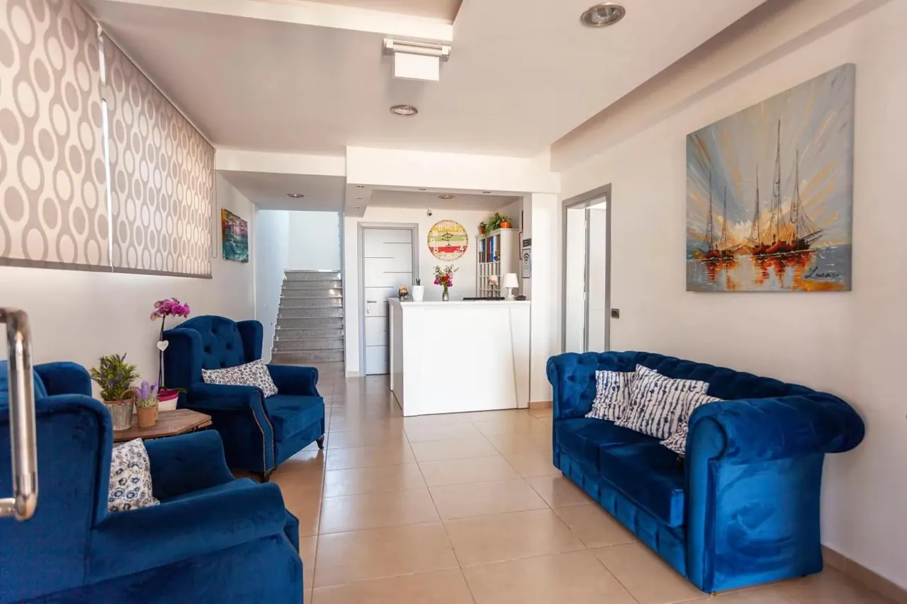 A reception lounge with deep blue velvet sofas and armchairs on pale tiles