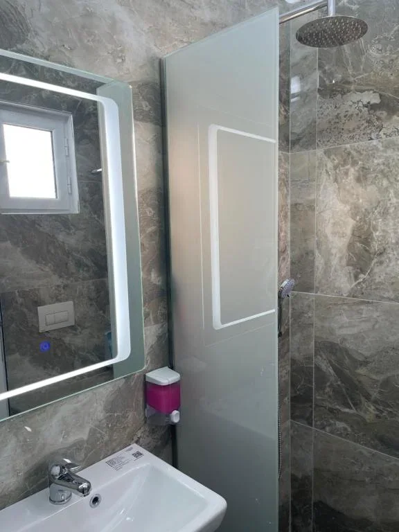 A grey marble bathroom at Hotel Frida with a rain shower behind a glass screen
