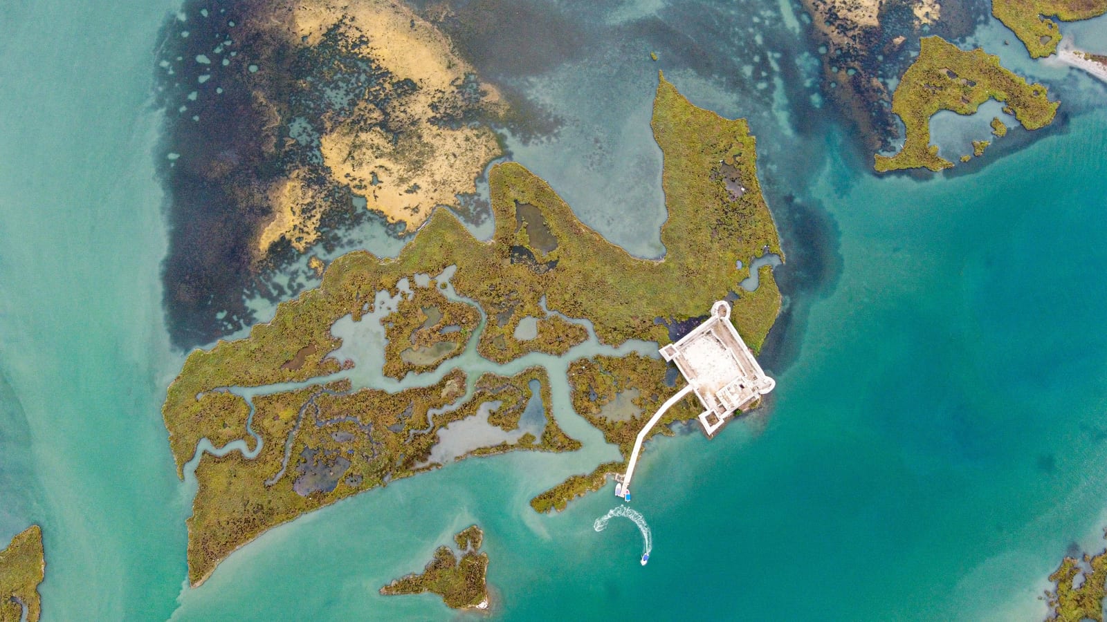 Aerial of a fortified ruin on a marshy lagoon island in the Butrint area near Ksamil — a key day-trip site on a Saranda-Ksamil split stay