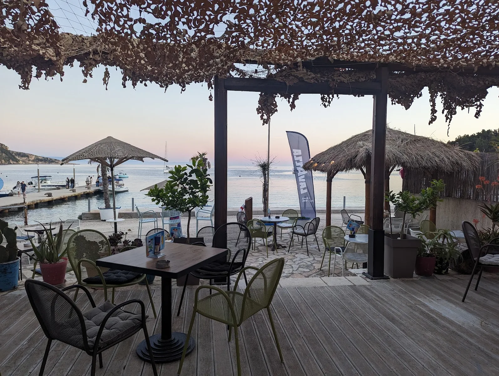 Sunset view from Manolo Beach Bar's wooden deck on Spile promenade in Himara