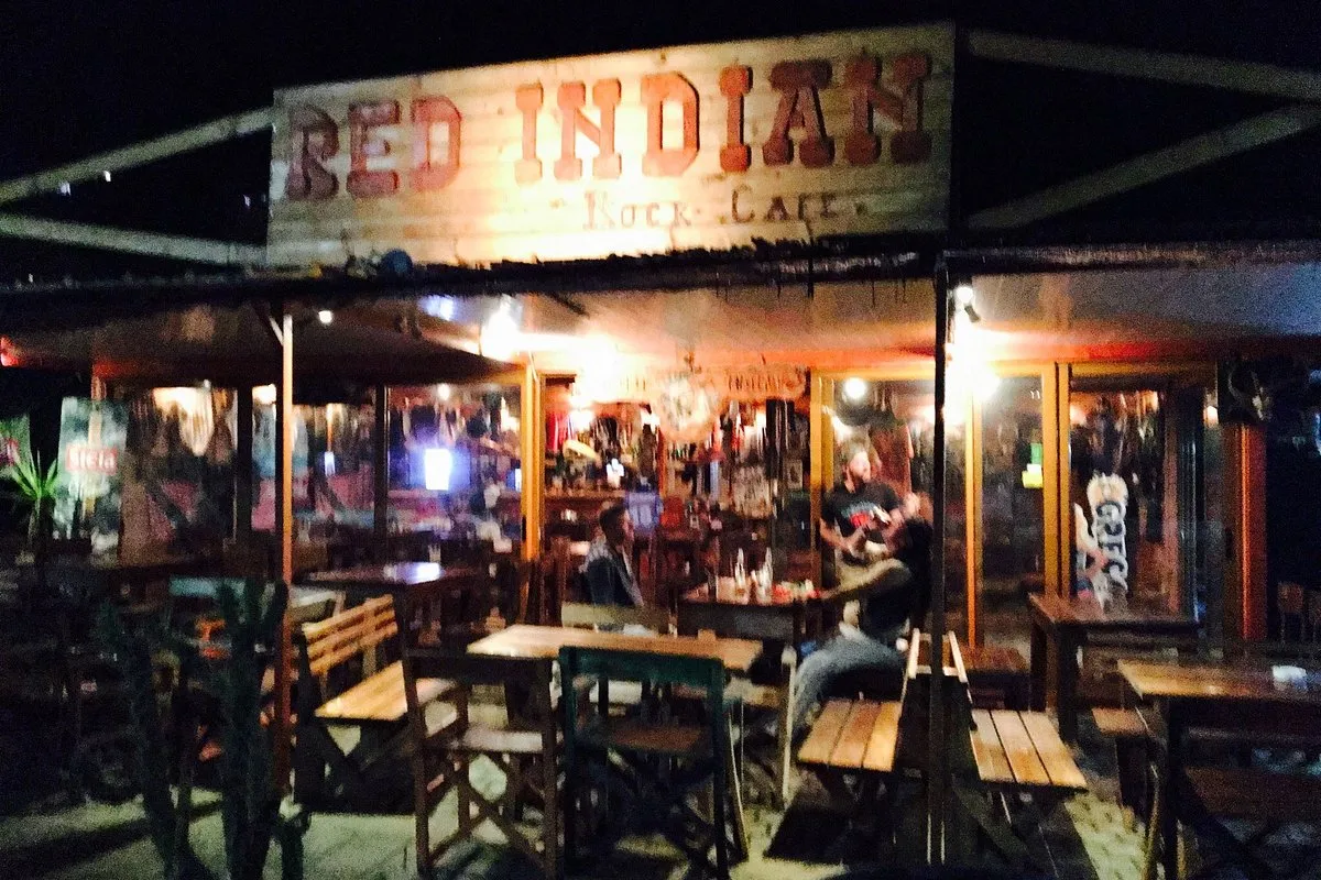 Quirky rock-themed facade of Red Indian Rock Cafe with its painted sign and red chairs on the highway