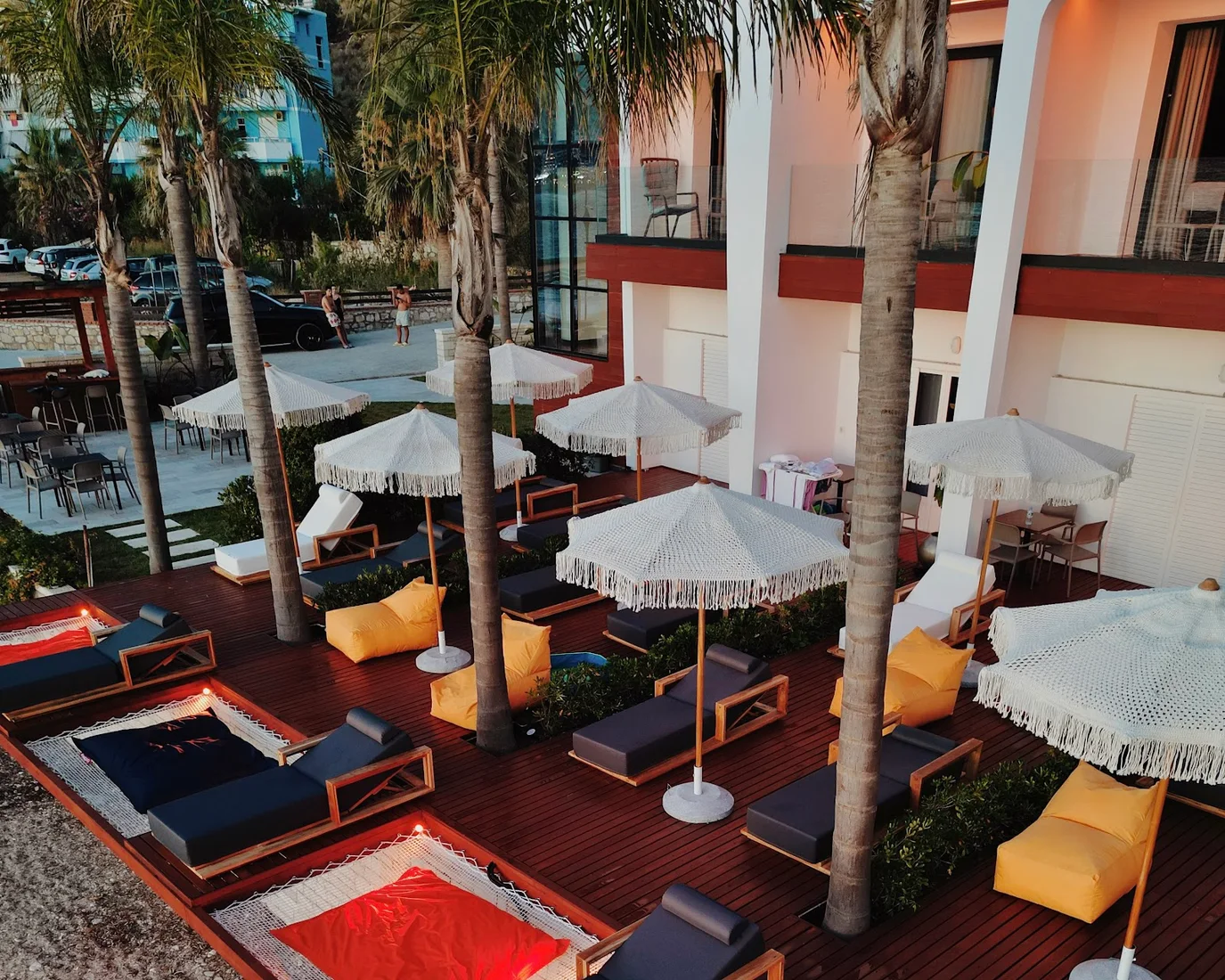 Macramé sun umbrellas and loungers on the beach deck at Oniro by Iliria Palace, Himare