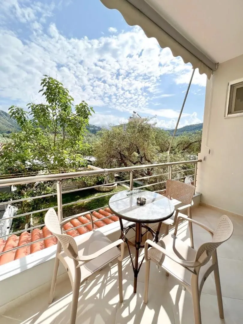 A balcony above the terracotta porch roof looking into the olive grove and up to the mountains