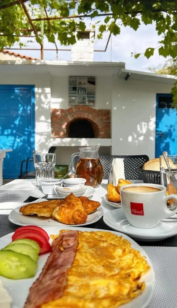 Breakfast laid under the grape vine, facing the whitewashed outbuilding with its brick wood oven and bright blue doors
