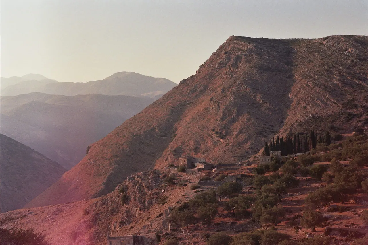 Abandoned stone houses on the olive terraces of old Qeparo, the ridge behind them