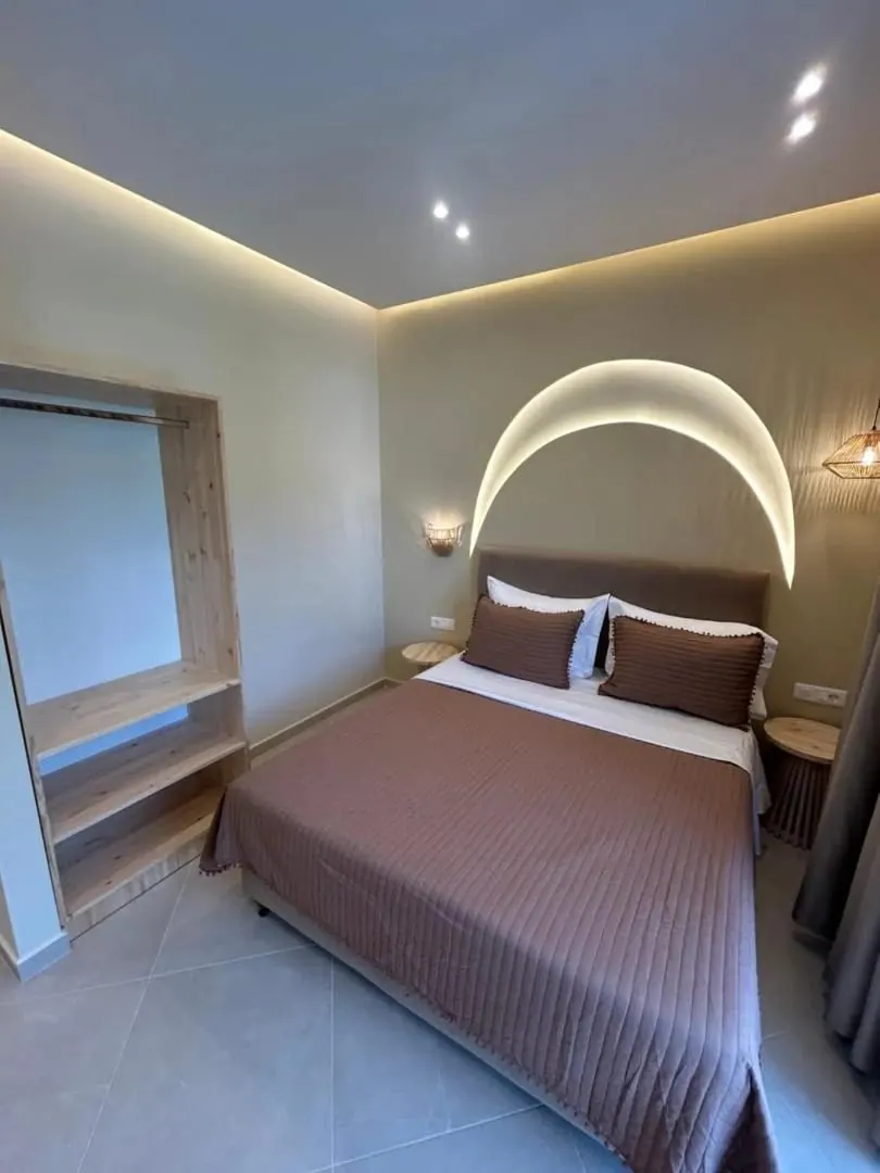 A double room with a domed arc of concealed light above the bed and an open timber wardrobe