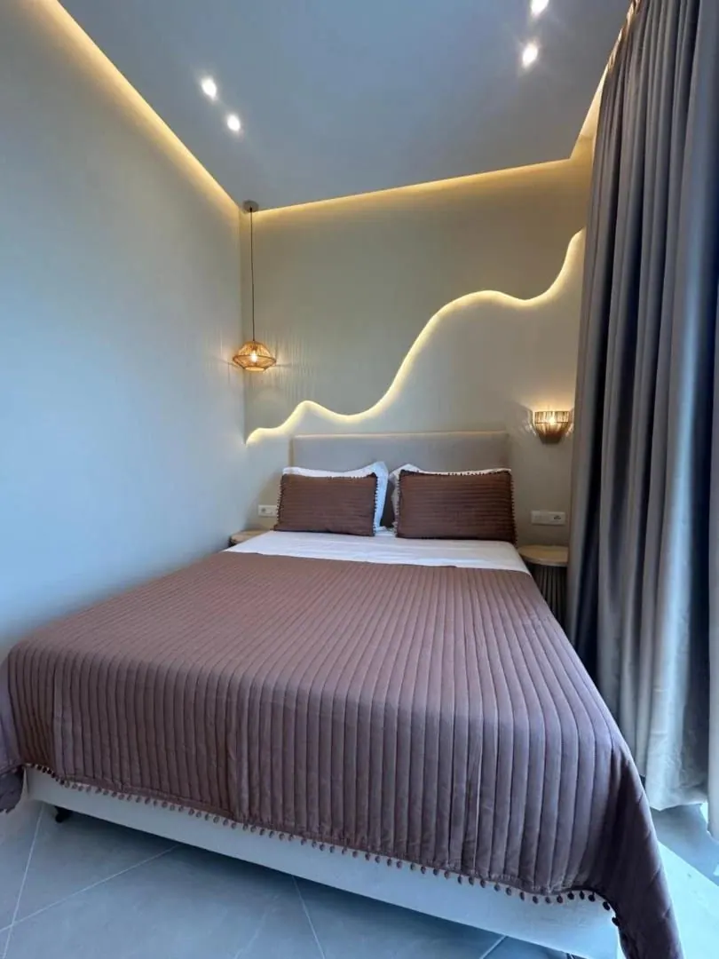 A double room with a wave of concealed light above the bed and a floor-length curtain