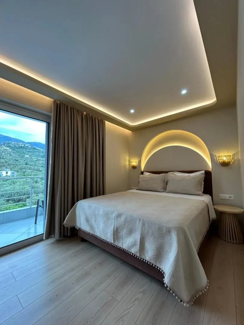 A mountain-view room with a domed arc of light over the bed and the hillside through the window