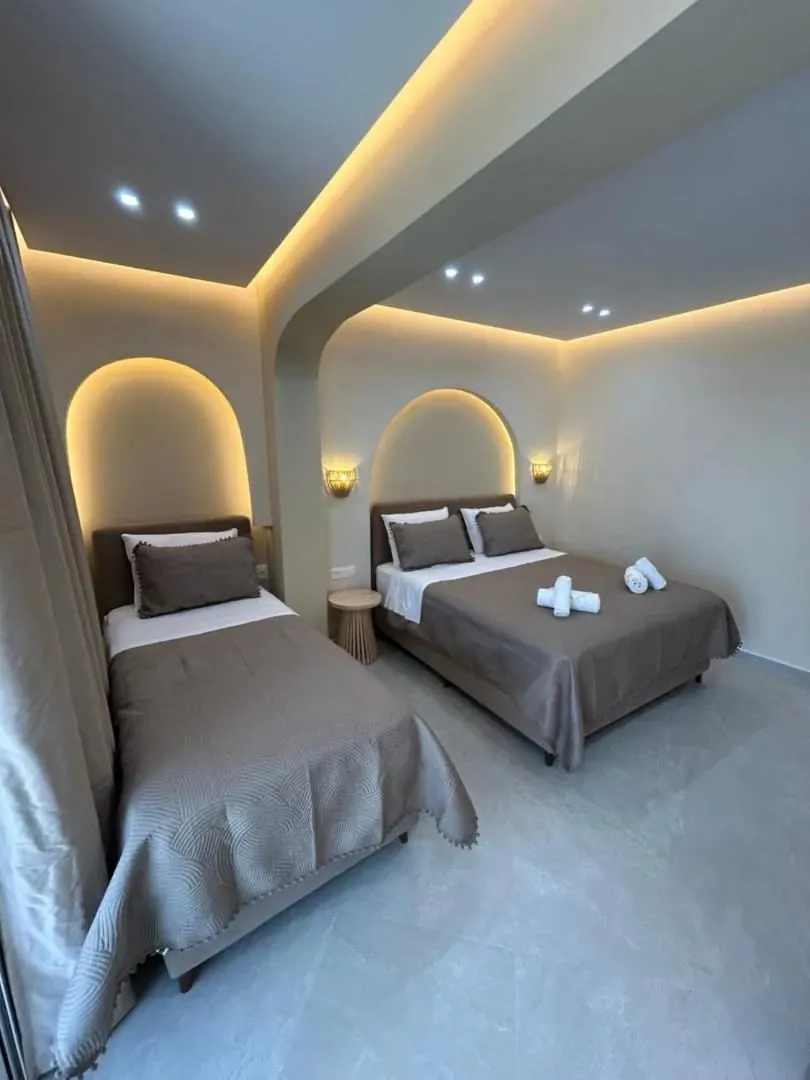 A triple room with two beds, each under its own arc of concealed light