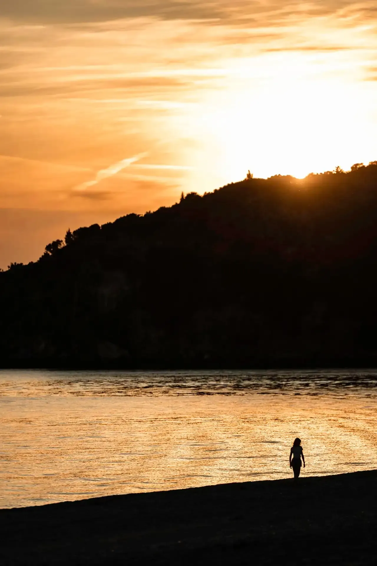 The sun going down behind the headland at Livadhi, the water gone gold and a single figure on the dark shore