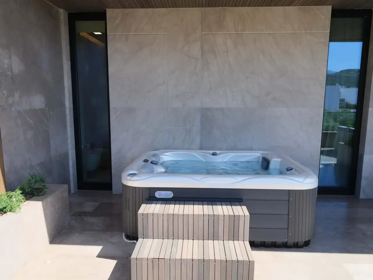 The jacuzzi on the Deluxe Suite balcony, timber steps up to it and marble walls around it