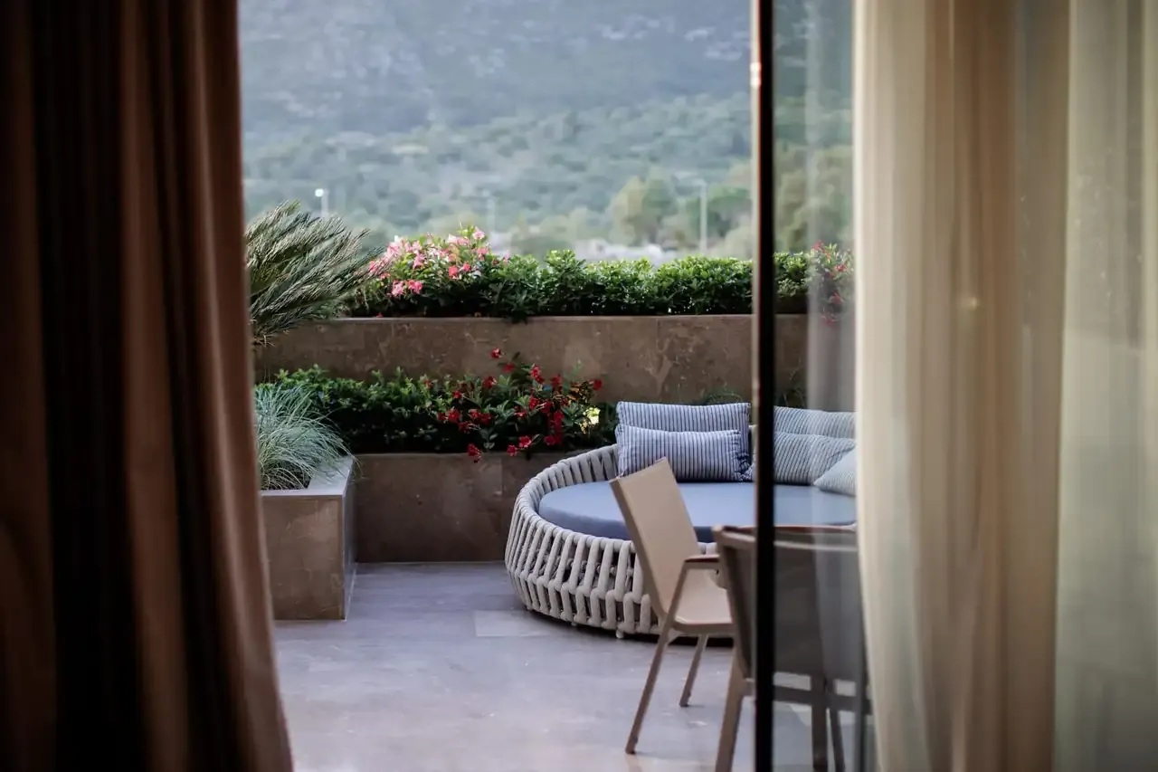 The balcony of a Junior Suite with Jacuzzi, planting along the rail and hills behind