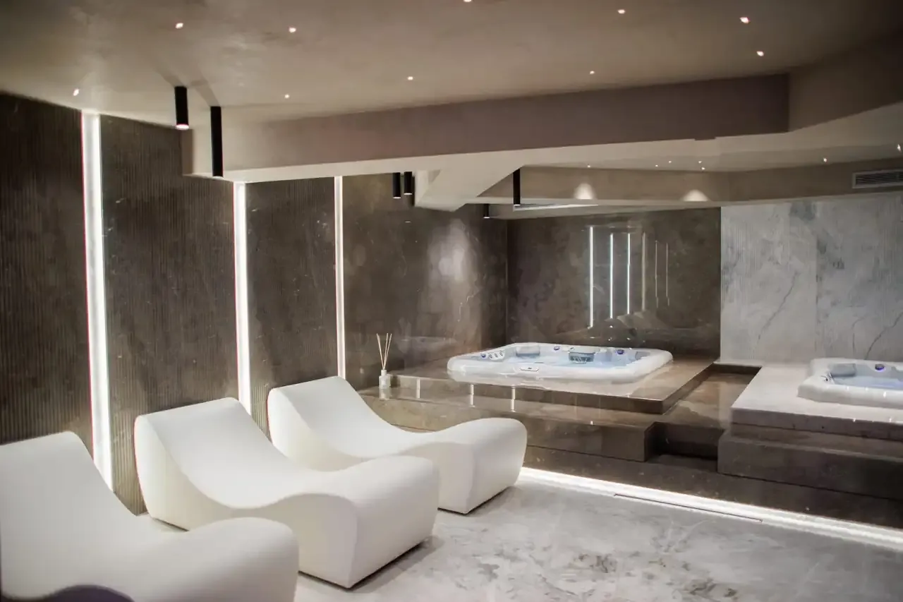 The jacuzzi room at Prado in dark marble with moulded white loungers beside it