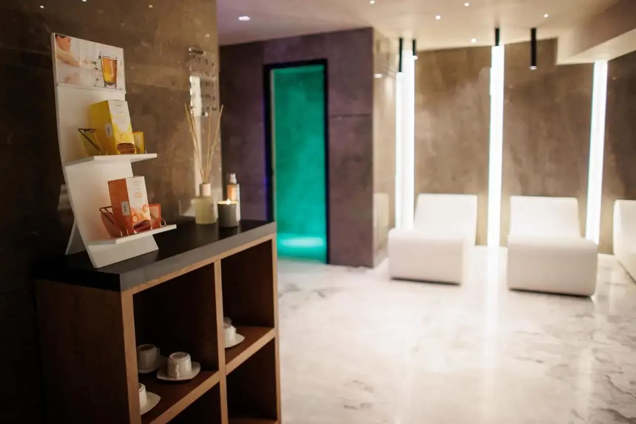 Moulded white loungers in the spa relaxation lounge beside a shelf of treatment products