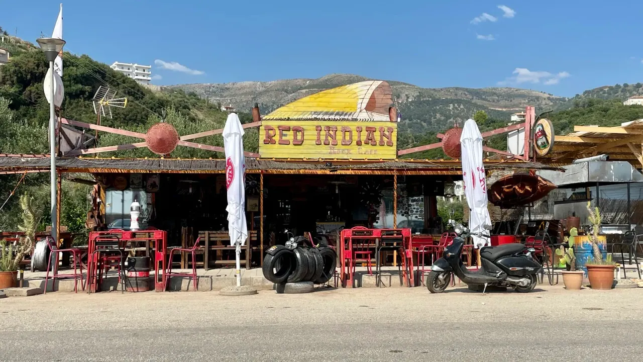 Quirky rock-themed facade of Red Indian Rock Cafe with its painted sign and red chairs on the highway