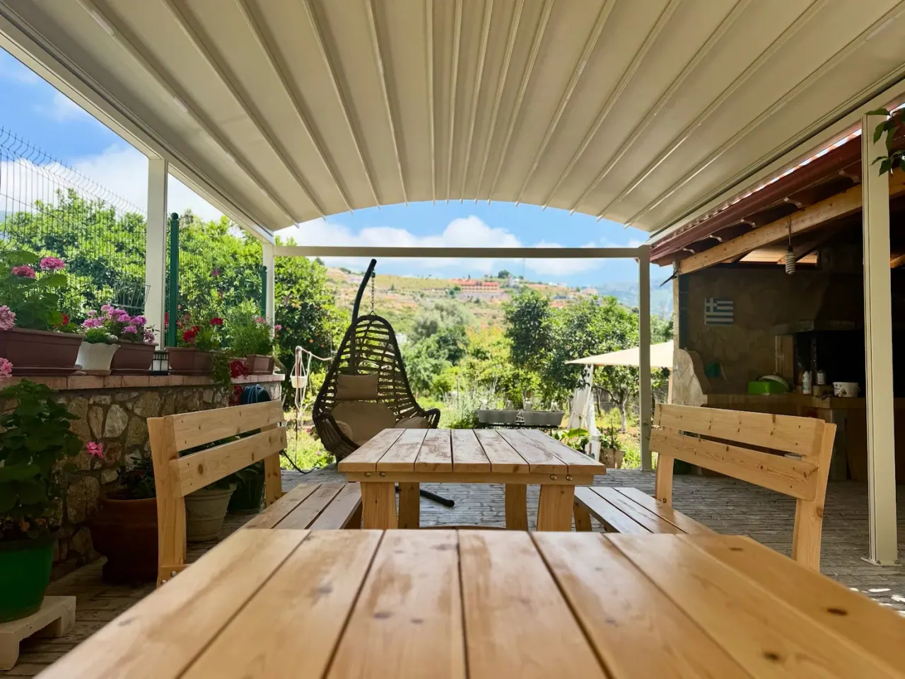 Covered wooden terrace with hanging chair and valley view at Elpis Guest House in Himara