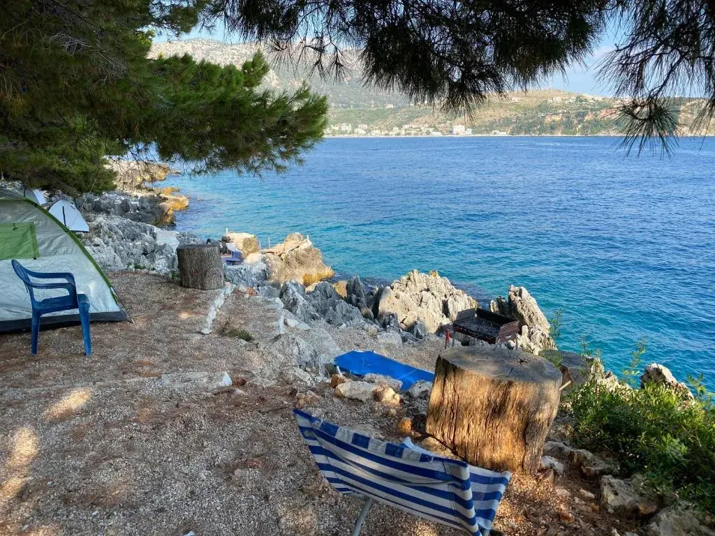 Tents pitched among pines on the rocky seaside headland at Pine Side Camp in Himara