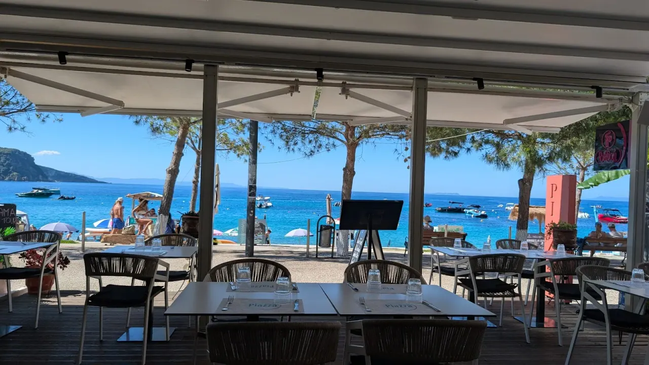 Seafront dining terrace with set tables overlooking the bay at Piazza Restaurant in Himara