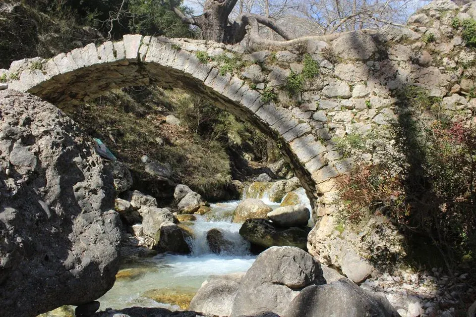 Old arched stone bridge spanning a clear stream in the Gjipe Canyon on the Albanian Riviera