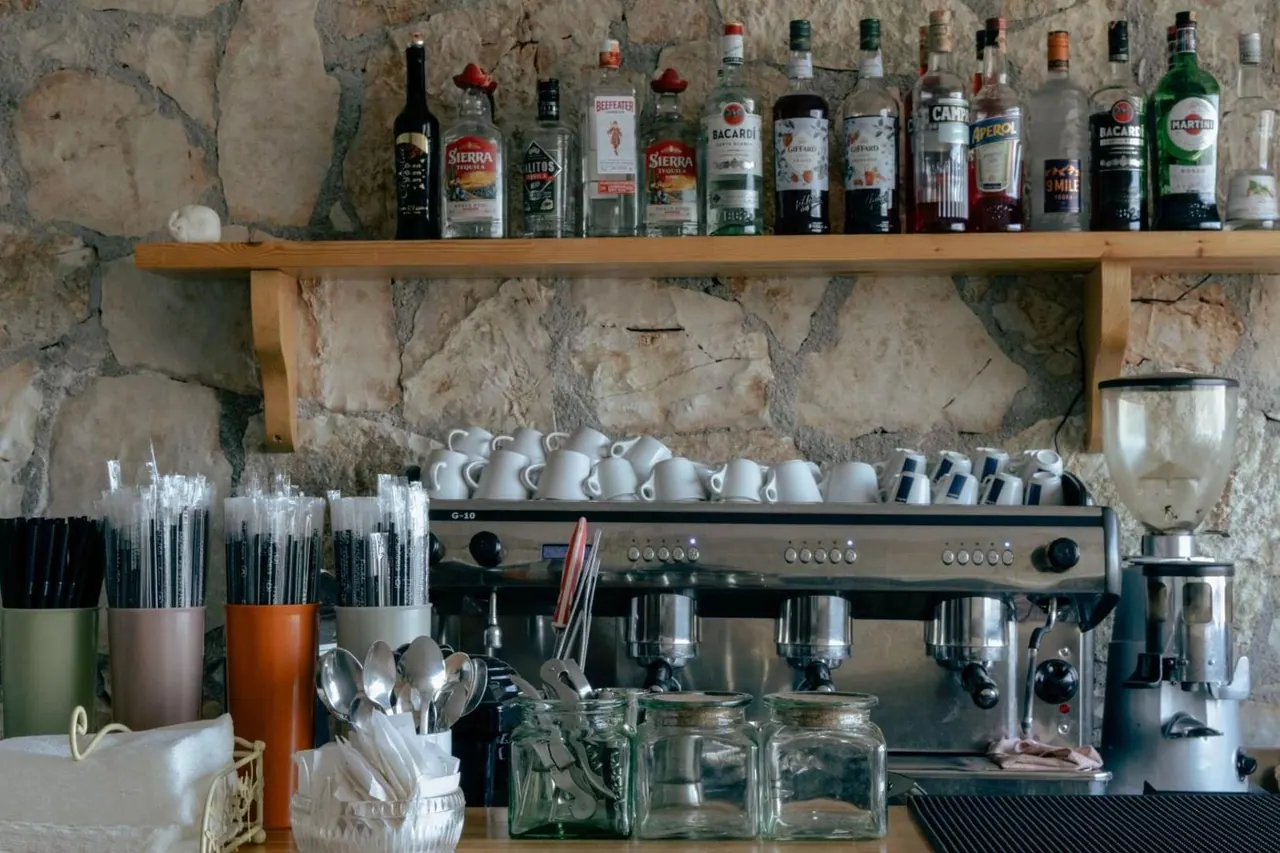 Spirit bottles on a timber shelf above glassware and an espresso machine