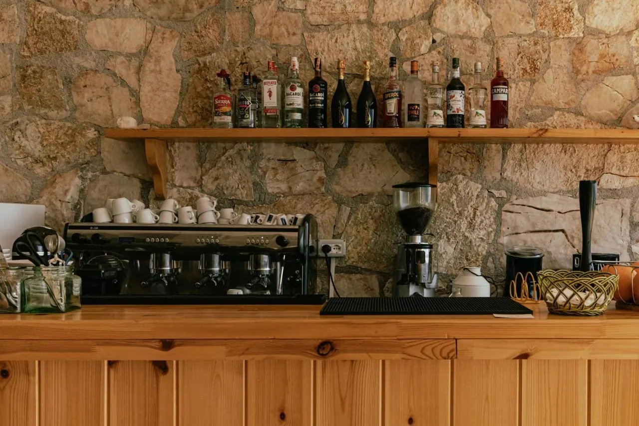 The bar built into a stone wall with a timber counter, an espresso machine and a shelf of bottles