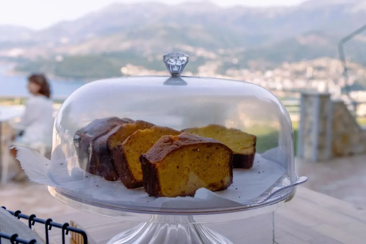 A sliced marble cake under a glass dome on a stand on the terrace