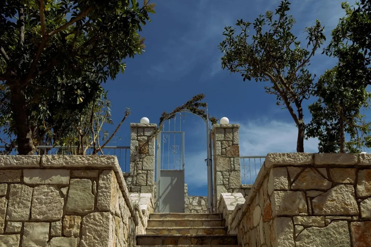 A white metal gate between two stone pillars at the top of the steps