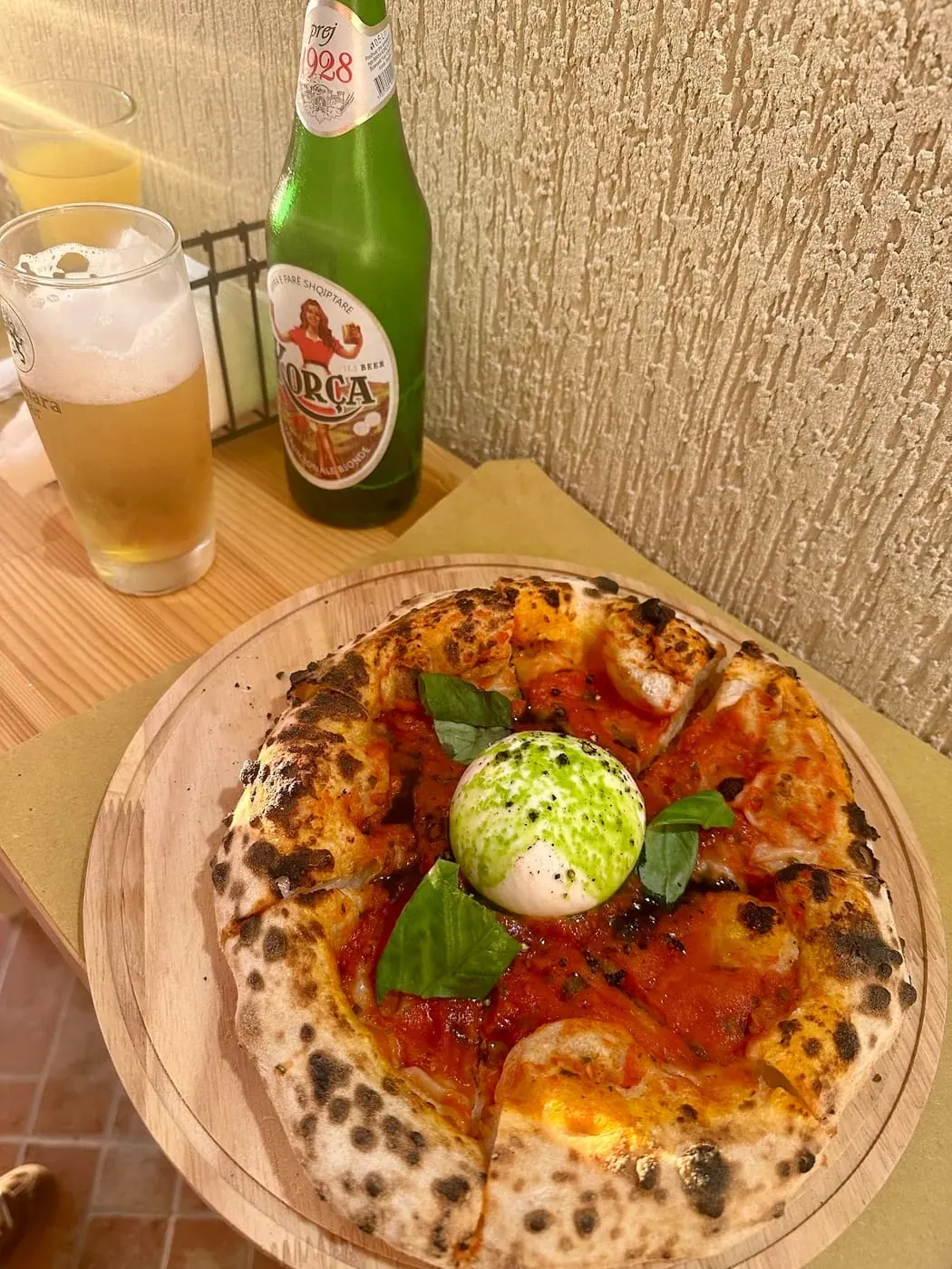 A pizza with a whole ball of burrata in the centre on a wooden board