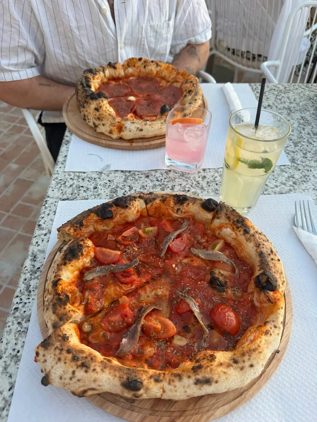 A tomato pizza scattered with anchovies and cherry tomatoes on a wooden board