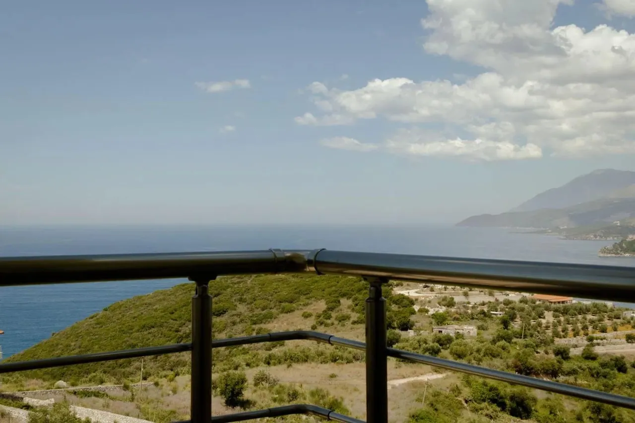 The view from a balcony rail across the wooded headland to the sea