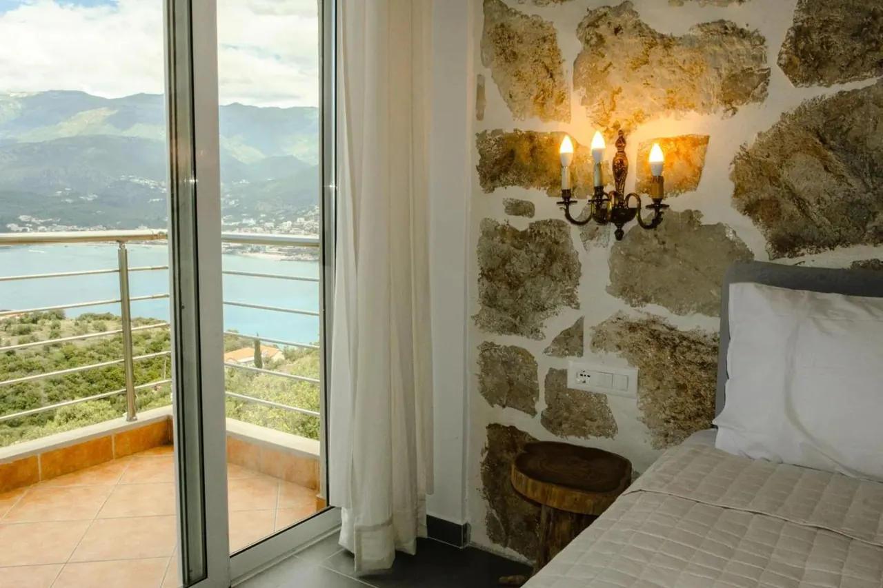The same room from the doorway, a wrought-iron candelabra on the stone wall above the bed