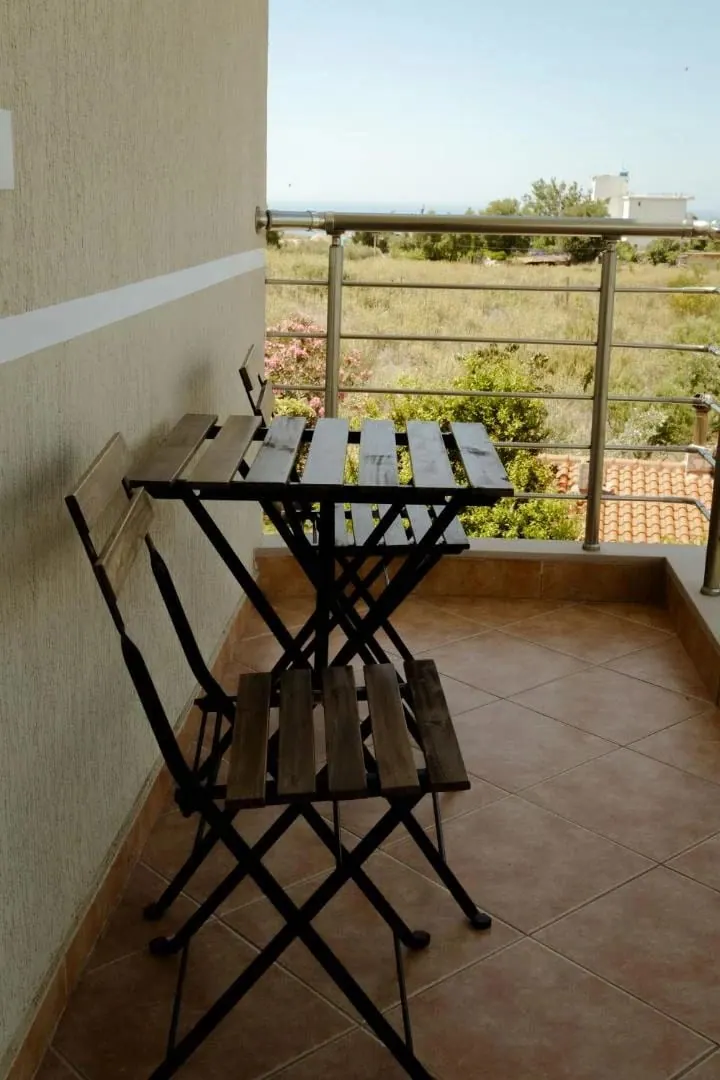 A folding table and two chairs on a tiled private balcony