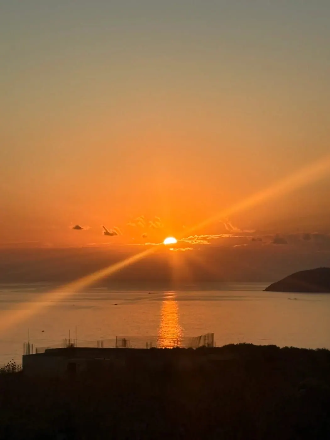 The sun going down into the open Ionian, rays fanning across the water