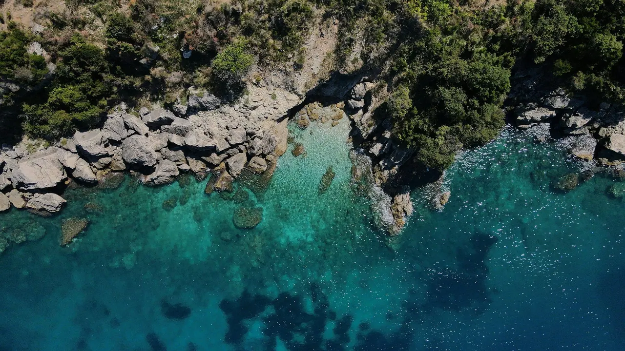 Clear turquoise Ionian water over pale rocks on the coast at Himarë, seen from above