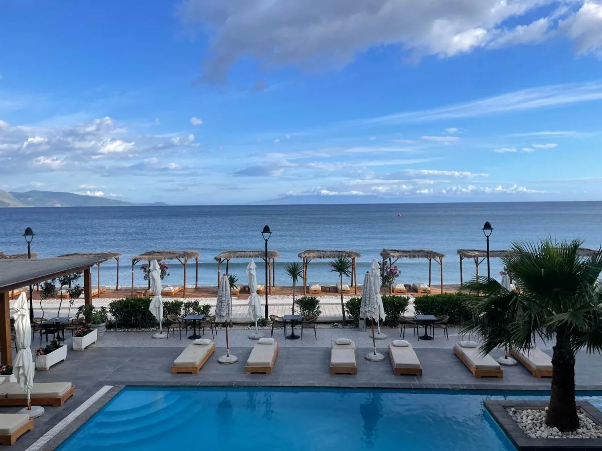 Loungers and folded parasols around the pool with the Ionian bay and the far headland beyond
