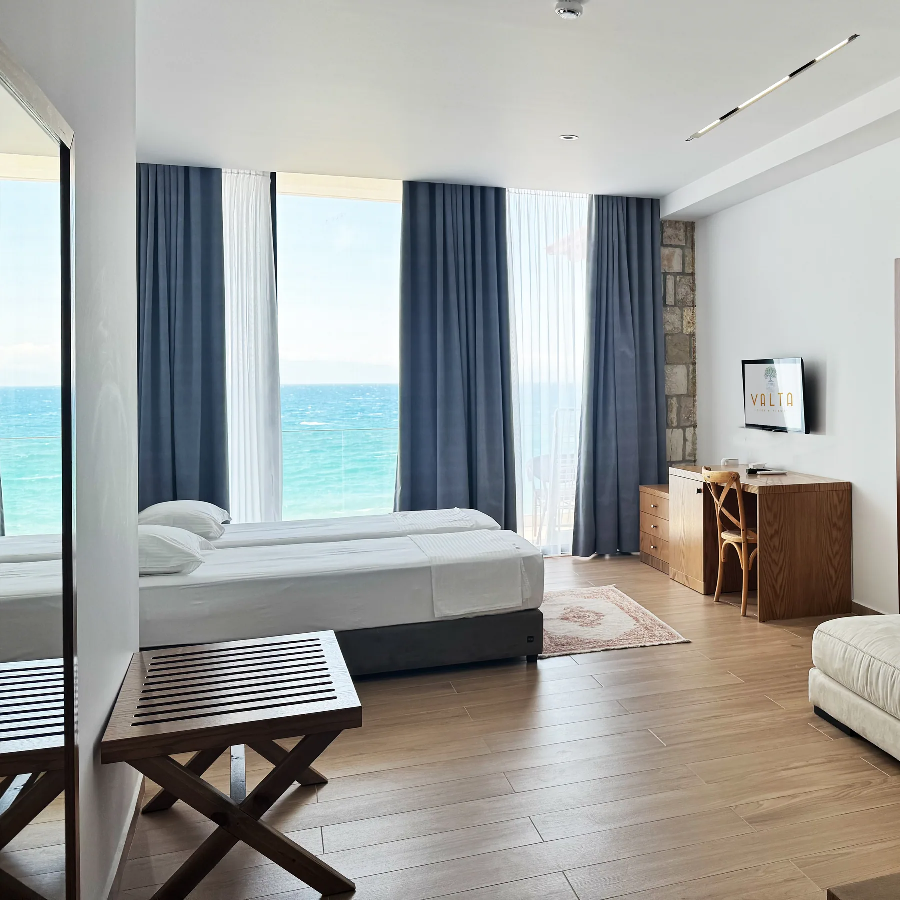 A sleeping area with grey curtains drawn back from a window filled by the bay