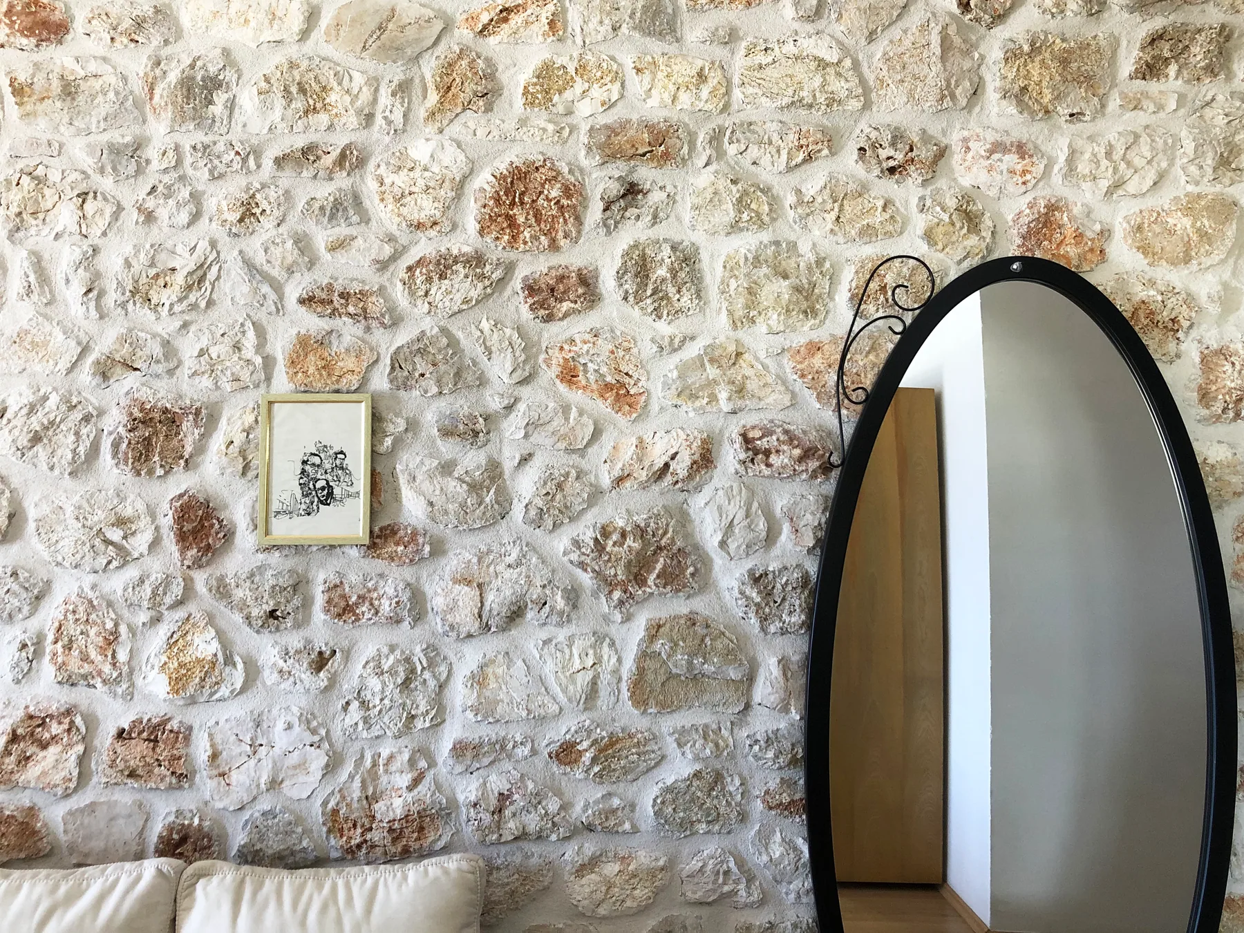 Beds under a beamed ceiling in a stone room with an arched door open to the balcony