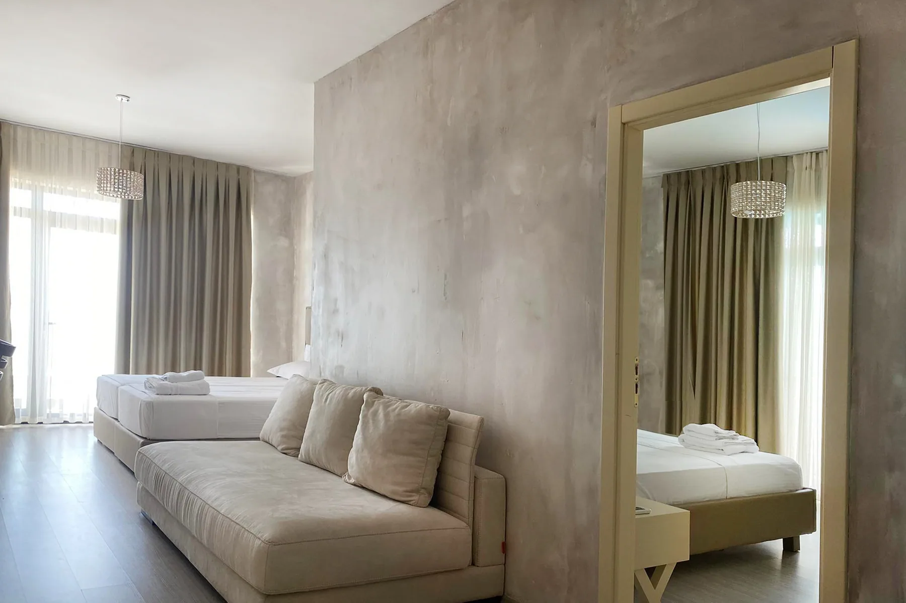 A long sofa in a plaster living area with a doorway through to the bedroom