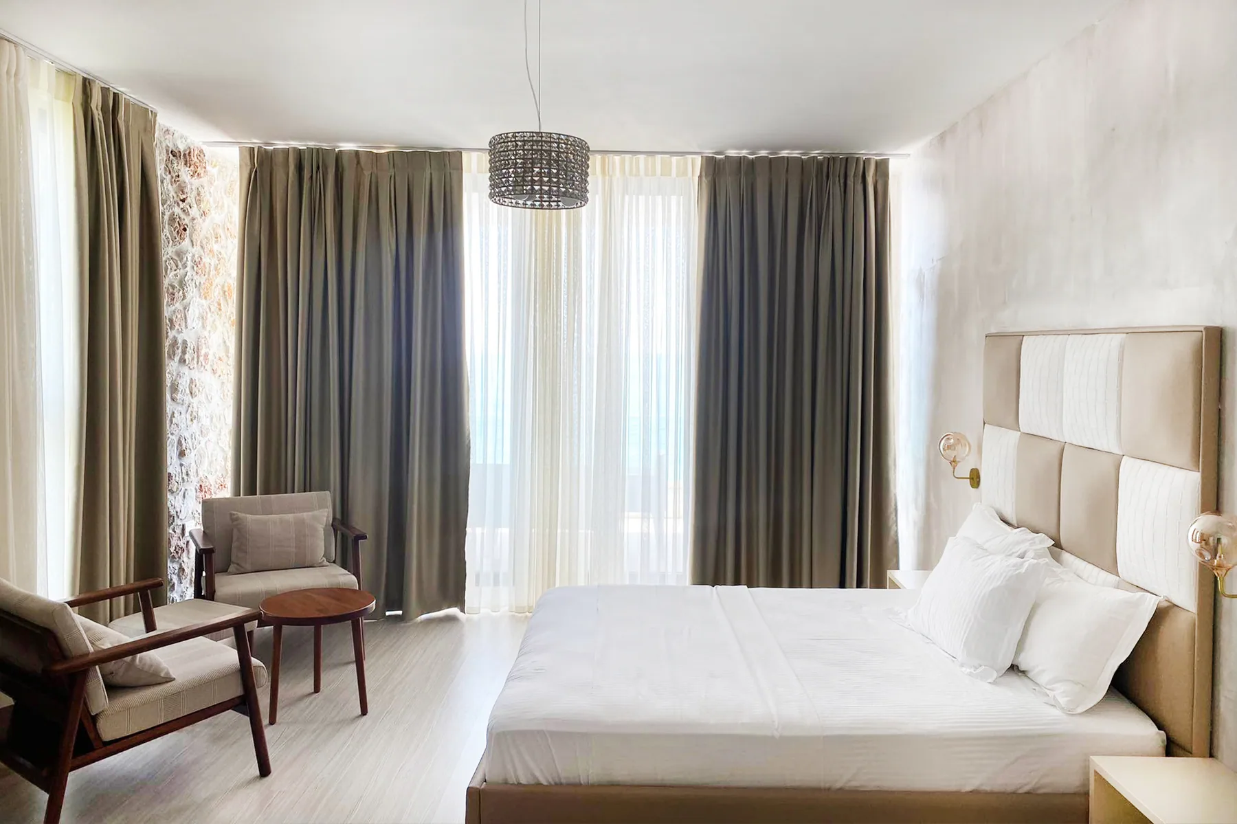 The same suite from the doorway, bed to the right and the sea beyond the curtains
