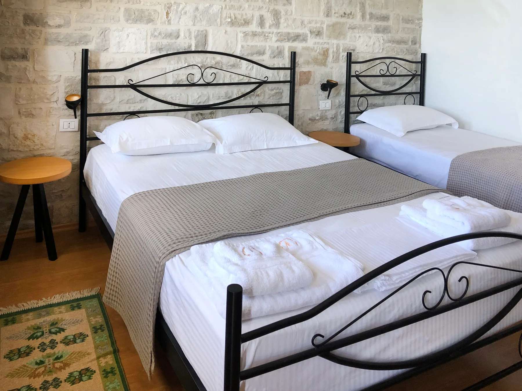 Two beds with wrought-iron headboards and a patterned rug on the timber floor
