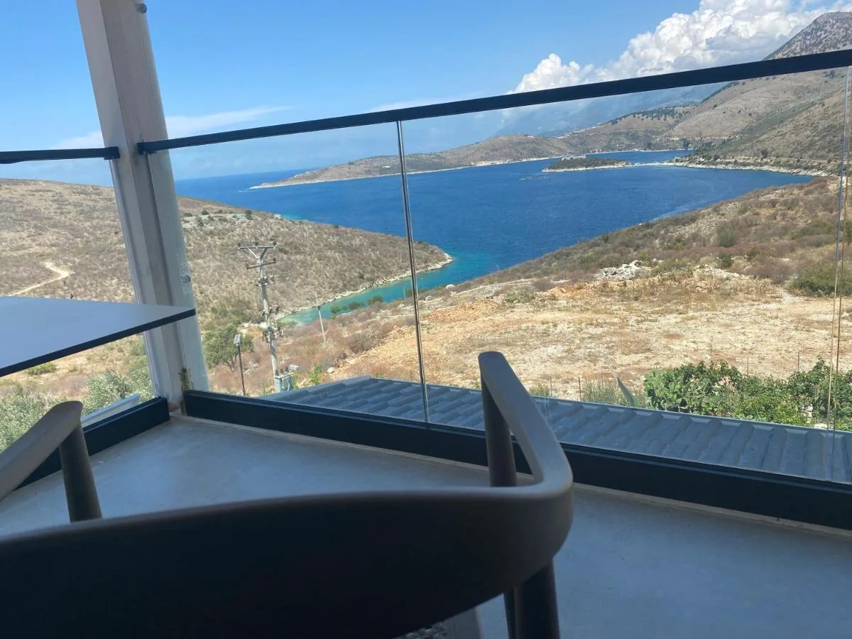 The inlet and the isthmus of Porto Palermo seen over a glass balcony balustrade